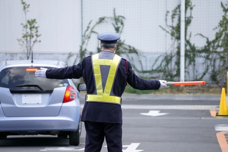 駐車場で交通誘導する警備員